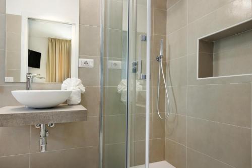 聖安蒂奧科的住宿－Mercury Beach Hotel，一间带玻璃淋浴间和水槽的浴室