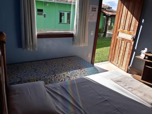 a bedroom with a bed and a window with a door at Pousada Capitão Cipoeiro in Serra do Cipo