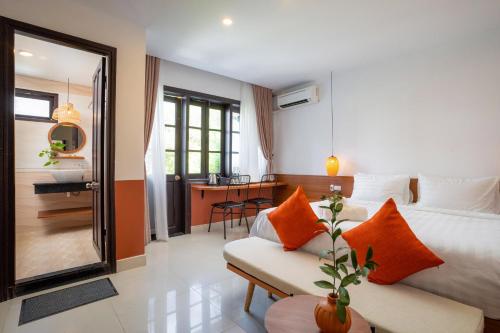 a bedroom with a bed and a couch and a desk at Hoianese Center Hotel - Truly Hoi An in Hoi An