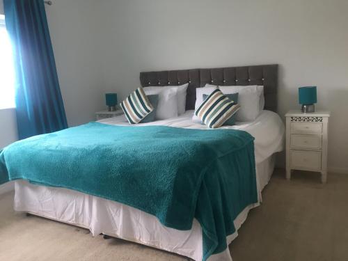 a bedroom with a large bed with a blue blanket at Sea Bean 2 Bedroom House Manorbier Tenby Pet Friendly in Manorbier