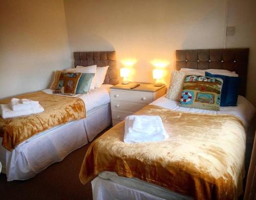 a bedroom with two beds and a dresser with lamps at Sea Bean 2 Bedroom House Manorbier Tenby Pet Friendly in Manorbier