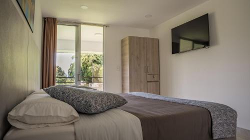 1 dormitorio con 1 cama y TV en la pared en Hotel Palo Grande CF Pereira en Pereira