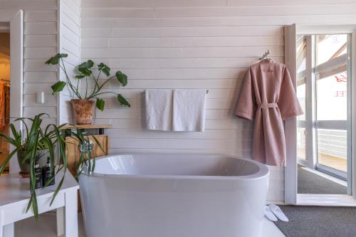 a bath tub in a bathroom with a pink robe at The Lofts Boutique Hotel in Knysna