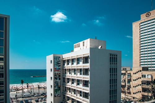 un edificio blanco alto con la playa en el fondo en Selina Frishman Tel Aviv, en Tel Aviv