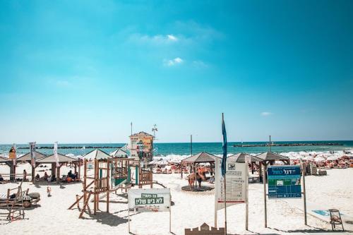 a beach with chairs and umbrellas and the ocean at Selina Frishman Tel Aviv in Tel Aviv