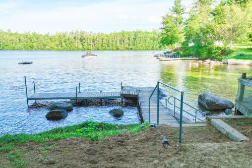 a dock in the middle of a lake with a boat at Boulder Pointe Cottage in Raymond
