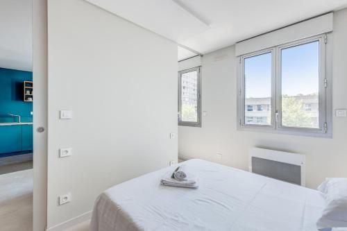 une chambre blanche avec un lit et deux fenêtres dans l'établissement Appartement Cyan - Welkeys, à Lyon