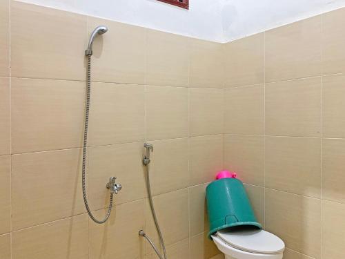 La salle de bains est pourvue d'une douche et de toilettes avec un cylindre vert. dans l'établissement OYO 91657 Penginapan Radja Jeneponto, à Pannara