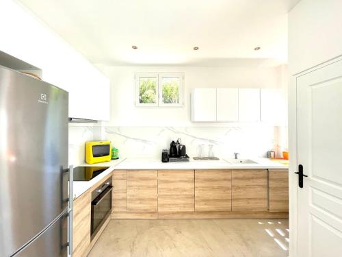 une cuisine avec des armoires blanches et un réfrigérateur en acier inoxydable dans l'établissement Très jolie Villa Bianca, maison avec jardin privé à Deauville, à Deauville