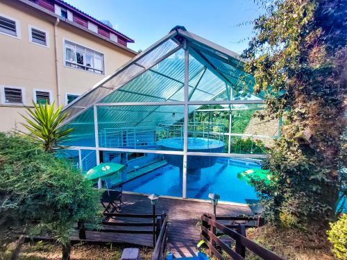una casa de cristal con piscina frente a un edificio en Hotel Fazenda Golden Park Campos do Jordão, en Campos do Jordão