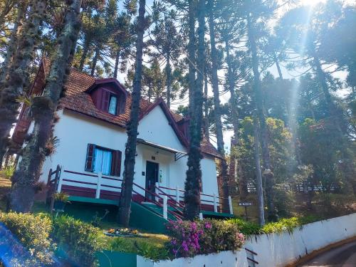 a white house in the woods with trees at Hotel Fazenda Golden Park Campos do Jordão in Campos do Jordão