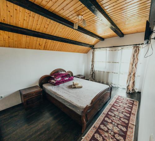 a bed in a room with a wooden ceiling at Casa Costea in Gura Humorului