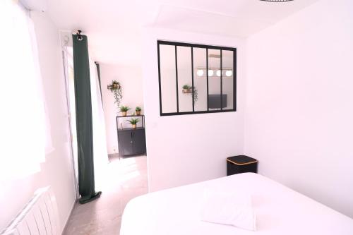 a white bedroom with a bed and a mirror at La Cosy House in Evry-Courcouronnes