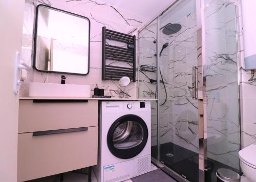 a bathroom with a washing machine and a shower at La Cosy House in Evry-Courcouronnes