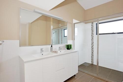 Baño blanco con lavabo y espejo en Panorama at Jervis Bay I Pet Friendly I 15 Mins to Hyams Beach en Bewong