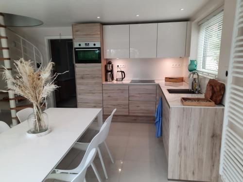 uma cozinha com armários brancos e uma mesa e cadeiras brancas em Holiday Home Mooi-Gemmenich em Plombières
