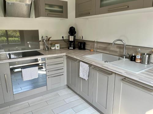 une cuisine blanche avec un évier et un comptoir dans l'établissement Côte d’Opale -Maison chaleureuse «au bois dormant», à Wadenthun