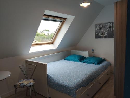 Un dormitorio con una cama con almohadas azules y una ventana en Chez la Québécoise - chambre d'hôtes, en Bourg-Blanc