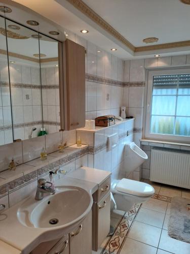 ein Badezimmer mit einem Waschbecken, einem WC und einem Spiegel in der Unterkunft Ferienwohnung Schleiten in Püttlingen