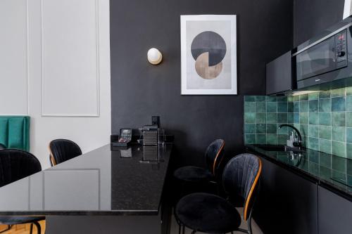 a kitchen with a black counter and black chairs at Wawel Boutique Residence - Krakow Old Town in Kraków