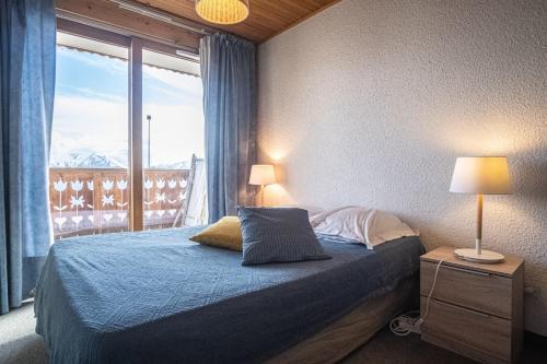 a bedroom with a bed and a large window at Apartment with a balcony and superb view - Huez - Welkeys in LʼHuez