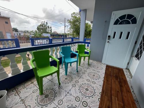 einen Balkon mit vier Stühlen und einer Tür in der Unterkunft 1A - Large Beach House near Crash Boat Beach in Aguadilla