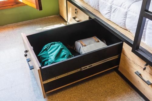 an open drawer of a bunk bed with two bags at Faz Hostel in Cordoba
