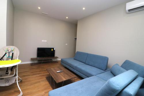 a living room with a blue couch and a tv at Vila ELARAD in Vlorë