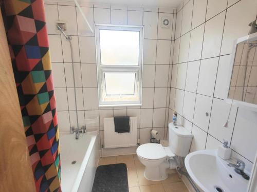 a bathroom with a toilet and a tub and a sink at Lovely 3 bedroom serviced apartment in Leytonstone in London