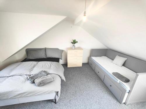 a white bedroom with a bed and a bench at Lovely 3 bedroom serviced apartment in Leytonstone in London