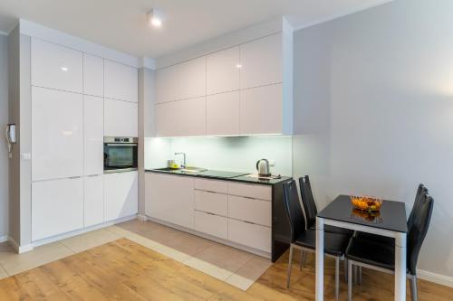a kitchen with white cabinets and a table and chairs at FIRST -- Green Żoliborz Apartment 4 in Warsaw