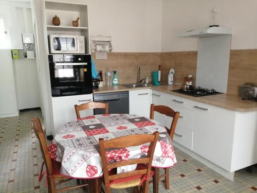 una cucina con tavolo e sedie e una cucina con forno a microonde di Gîte de la Casse a Channay-sur-Lathan
