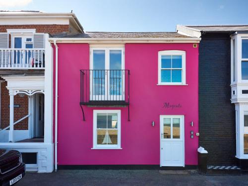 ein rosa Haus mit einer weißen Tür in der Unterkunft Magenta - A stunning Seafront house with lovely and uninterrupted Beach Views - Aldeburgh Coastal Cottages in Aldeburgh