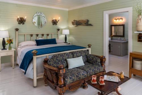 Maison D'Memoire Bed & Breakfast Cottages في Rayne: غرفة نوم بسرير واريكة وطاولة