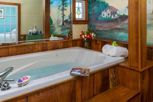 a bath tub in a bathroom with a painting at Maison D'Memoire Bed & Breakfast Cottages in Rayne