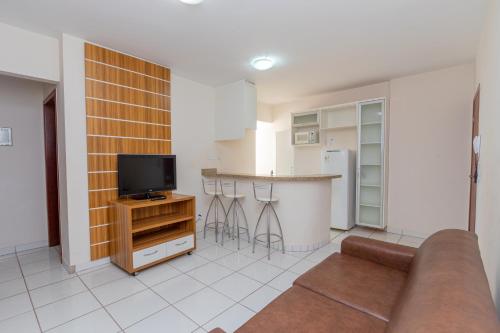 a living room with a couch and a kitchen at Toulon Flat Service in Caldas Novas