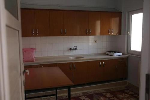 a kitchen with a sink and wooden cabinets and a window at Ümit 2 Termal Apart Pansiyon in Pamukkale