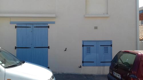 une voiture blanche garée à côté de deux portes bleues dans l'établissement Hippocampe - Jolie petite Maison de vacances à la Corniche, à Sète