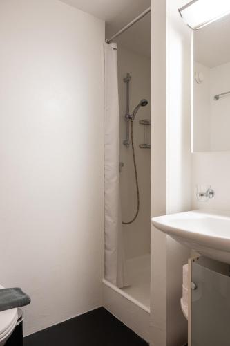 a white bathroom with a shower and a sink at Studio direkt im Zentrum, tolle Terrasse, Aussicht in Zermatt