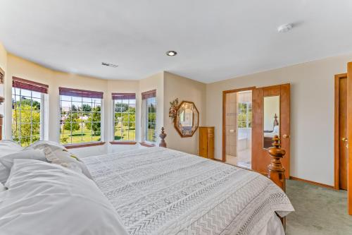 a bedroom with a large white bed with windows at House Of Serenity in East Wenatchee