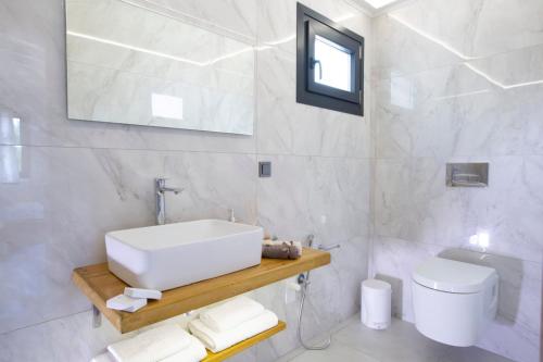 a white bathroom with a sink and a toilet at Lefkolia Retreat in Sivota