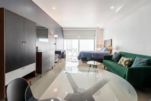 a living room with a glass table and a green couch at 600 sq ft in trendy area, 150 BPS fiber optic in Mexico City
