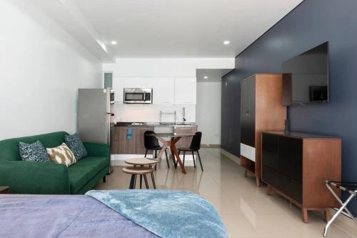 a bedroom with a green couch and a kitchen at 600 sq ft in trendy area, 150 BPS fiber optic in Mexico City