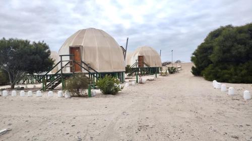 two domes in the middle of a desert with a dirt road at Camping Las Machas in Bahia Inglesa