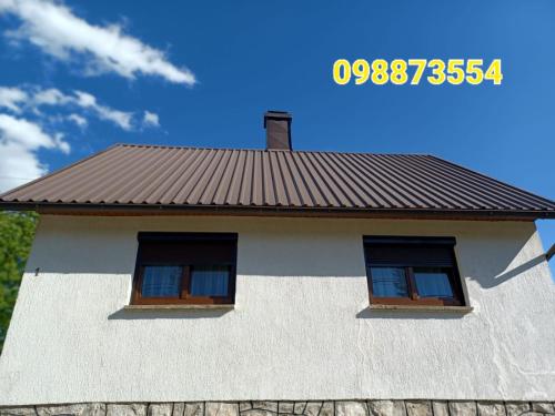 a white house with two windows and a roof at Apartman Šoljac in Perušić