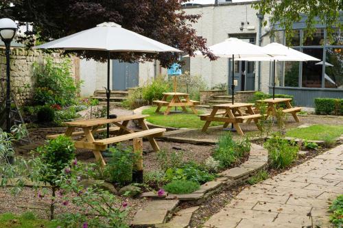 a group of picnic tables with umbrellas in a garden at The Inn South Stainley in Harrogate