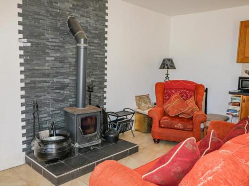 a living room with a fireplace and a red chair at Beehive Cottage in Kilbrittain