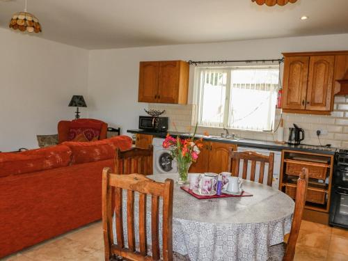 a kitchen and living room with a table and chairs at Beehive Cottage in Kilbrittain