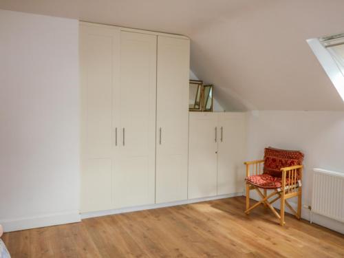 a room with white cabinets and a chair at Beehive Cottage in Kilbrittain