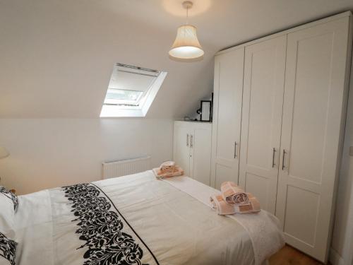 a bedroom with a bed with white cabinets and a skylight at Beehive Cottage in Kilbrittain
